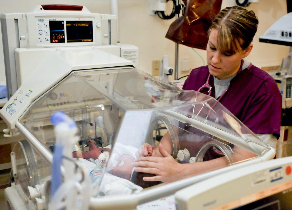 Flickr - Official U.S. Navy Imagery - A nurse examines a newborn baby..jpg” by MC2 John O'Neill Herrera/U.S. Navy is in the Public Domain Photo showing nurse touching infant in incubator