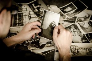 “photos-256887_960_720.jpg” by jarmoluk is licensed under CC0 Image showing person off camera looking at photo of a child, with photos on ground in background